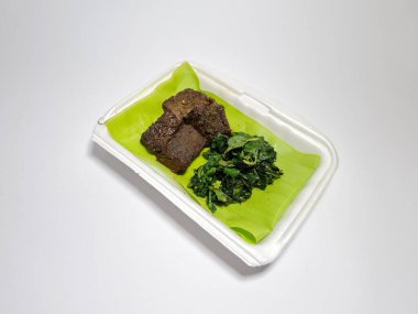 Beyaz kabın içinde yeşil sebzeli kızarmış et dilimleri.