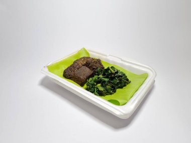 Beyaz kabın içinde yeşil sebzeli kızarmış et dilimleri.