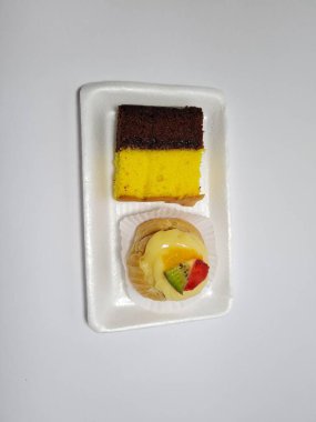 Beyaz bir kabın içinde Endonezya atıştırmalıkları, sandviçler ve meyve suyu.