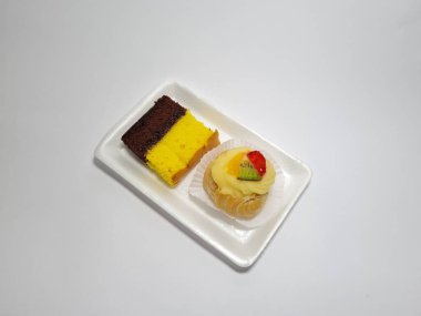 Beyaz bir kabın içinde Endonezya atıştırmalıkları, sandviçler ve meyve suyu.