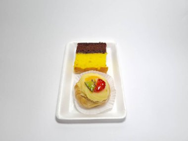 Beyaz bir kabın içinde Endonezya atıştırmalıkları, sandviçler ve meyve suyu.