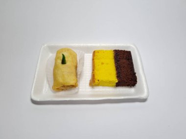 Beyaz bir kapta tipik Endonezya atıştırmalıkları, sandviçler ve börekler.