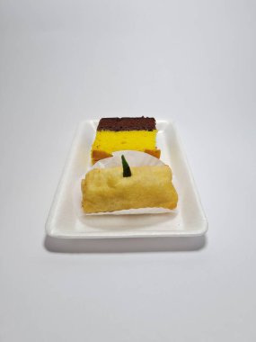 Beyaz bir kapta tipik Endonezya atıştırmalıkları, sandviçler ve börekler.