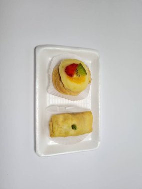 Beyaz bir kabın içinde tipik Endonezya atıştırmalıkları, meyveli ekler ve börekler.