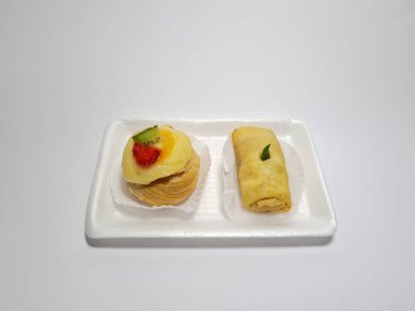 Beyaz bir kabın içinde tipik Endonezya atıştırmalıkları, meyveli ekler ve börekler.