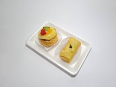 Beyaz bir kabın içinde tipik Endonezya atıştırmalıkları, meyveli ekler ve börekler.