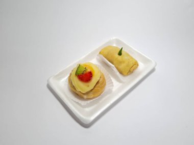 Beyaz bir kabın içinde tipik Endonezya atıştırmalıkları, meyveli ekler ve börekler.