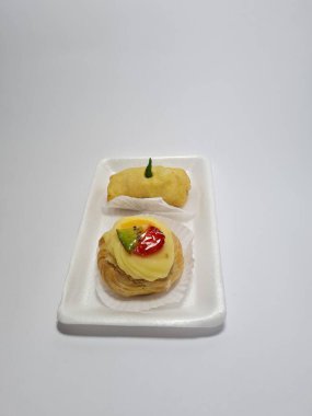 Beyaz bir kabın içinde tipik Endonezya atıştırmalıkları, meyveli ekler ve börekler.