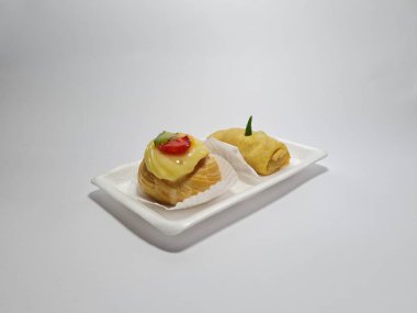 Beyaz bir kabın içinde tipik Endonezya atıştırmalıkları, meyveli ekler ve börekler.