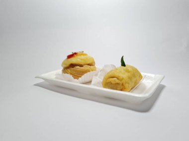 Beyaz bir kabın içinde tipik Endonezya atıştırmalıkları, meyveli ekler ve börekler.