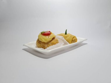 Beyaz bir kabın içinde tipik Endonezya atıştırmalıkları, meyveli ekler ve börekler.