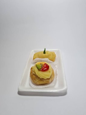 Beyaz bir kabın içinde tipik Endonezya atıştırmalıkları, meyveli ekler ve börekler.