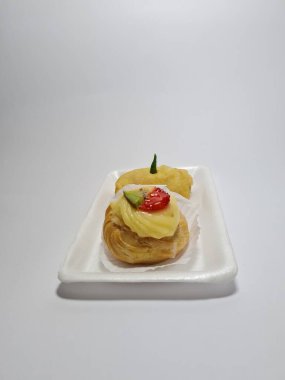 Beyaz bir kabın içinde tipik Endonezya atıştırmalıkları, meyveli ekler ve börekler.