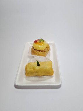 Beyaz bir kabın içinde tipik Endonezya atıştırmalıkları, meyveli ekler ve börekler.