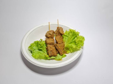 Beyaz tabakta yeşil marullu sığır eti.