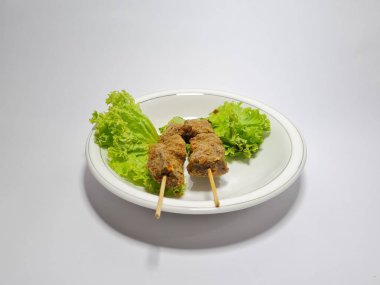 Beyaz tabakta yeşil marullu sığır eti.