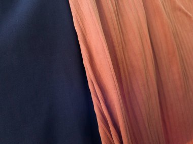 Katlanmış mavi ve turuncu kumaşın arka planında bir gölge var.