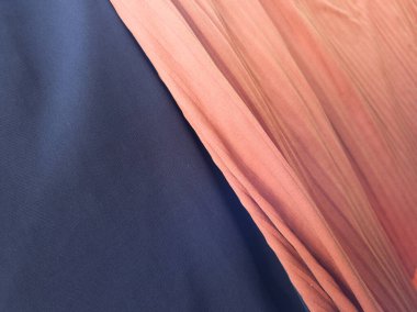 Katlanmış mavi ve turuncu kumaşın arka planında bir gölge var.