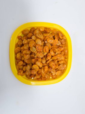 Fıstık koro adında bir atıştırmalık, kızarmış ve sarı bir kabın içinde tatlı ve baharatlı kırmızı baharat verilmiş.