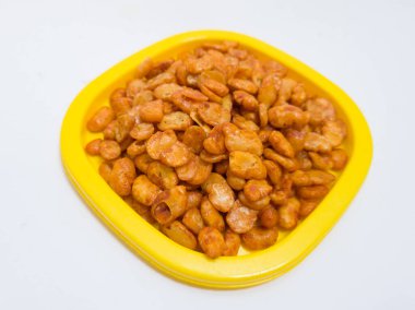 Fıstık koro adında bir atıştırmalık, kızarmış ve sarı bir kabın içinde tatlı ve baharatlı kırmızı baharat verilmiş.