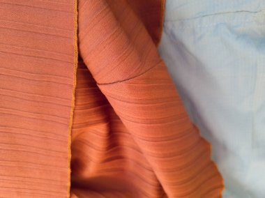 Soyut kumaş desenli turuncu arka plan ve açık mavi karışımı.