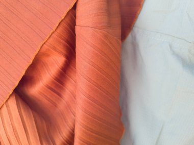 Soyut kumaş desenli turuncu arka plan ve açık mavi karışımı.