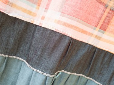 Soyut arkaplan desenli kumaş, turuncu, ekose, yeşil, siyah ve beyaz çizgilerle birleştirilmiş.