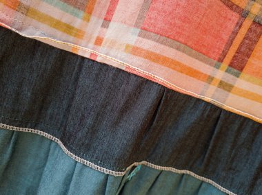 Soyut arkaplan desenli kumaş, turuncu, ekose, yeşil, siyah ve beyaz çizgilerle birleştirilmiş.