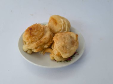 Beyaz bir tabakta servis edilen tatlı bir tat ile kaplanmış üç kızarmış kasava kaseti.