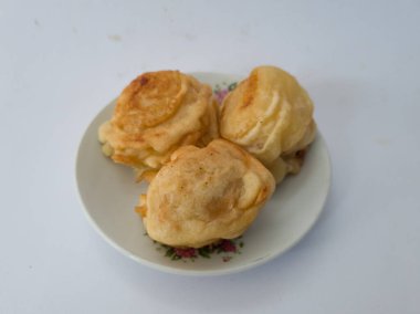 Beyaz bir tabakta servis edilen tatlı bir tat ile kaplanmış üç kızarmış kasava kaseti.