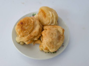 Beyaz bir tabakta servis edilen tatlı bir tat ile kaplanmış üç kızarmış kasava kaseti.