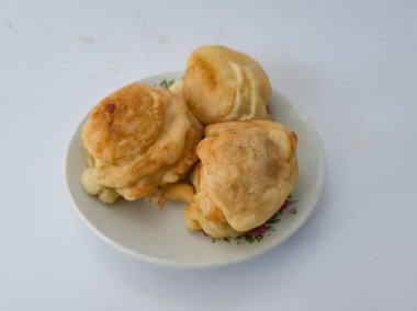 Beyaz bir tabakta servis edilen tatlı bir tat ile kaplanmış üç kızarmış kasava kaseti.