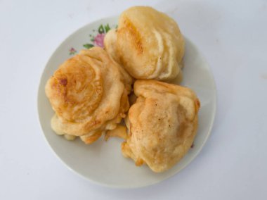 Beyaz bir tabakta servis edilen tatlı bir tat ile kaplanmış üç kızarmış kasava kaseti.