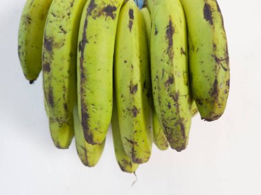 Beyaz bir binanın duvarında asılı yeşil muz