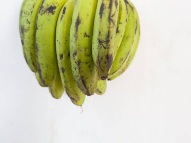 Beyaz bir binanın duvarında asılı yeşil muz