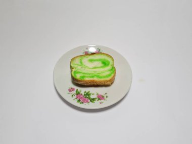 Beyaz tabakta yeşil pandan aromalı ekmek.
