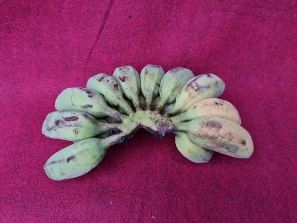 Banane Semi Mature Verdi Gialle Fondo Rosso — Foto Stock