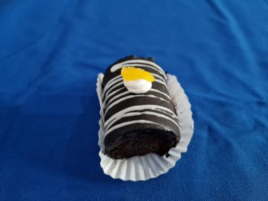 Çikolata ruloları reçel ve beyaz kremayla dolu mavi arka planda