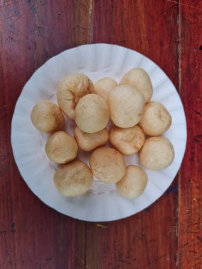 Yuvarlak kahverengi levrek krakerleri tahta bir masada beyaz bir konteynırda