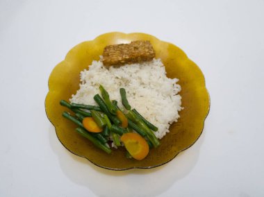 Uzun fasulye sebzeli beyaz pirinç artı kahverengi tabakta kızarmış tempeh.