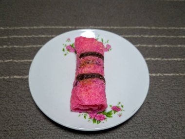 Beyaz bir tabakta rendelenmiş hindistan ceviziyle dolu kırmızı gözleme.