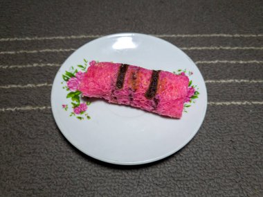 Beyaz bir tabakta rendelenmiş hindistan ceviziyle dolu kırmızı gözleme.