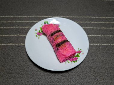 Beyaz bir tabakta rendelenmiş hindistan ceviziyle dolu kırmızı gözleme.