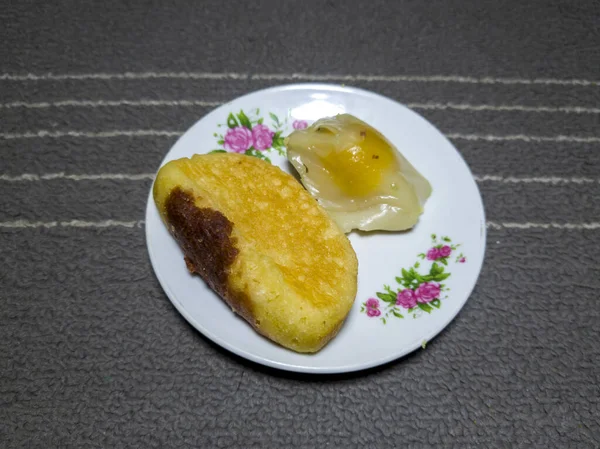 Chocolate flavored pukis cake and mendut cake filled with grated sweet head on a white plate