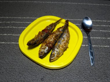 Sarı bir kabın içinde tatlı ve ekşi tatla pişirilmiş üç deniz balığı.