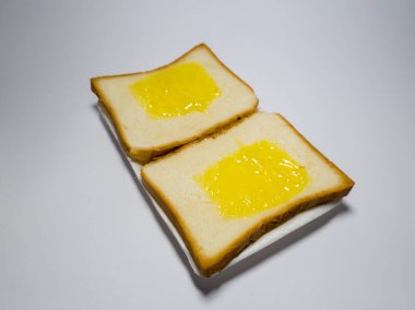 Beyaz bir kabın içinde ananas reçelli beyaz ekmek fotoğrafı.