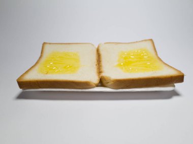 Beyaz bir kabın içinde ananas reçelli beyaz ekmek fotoğrafı.