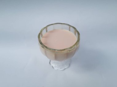 Beyaz arka planda cam bardakta çilek aromalı süt içilir.