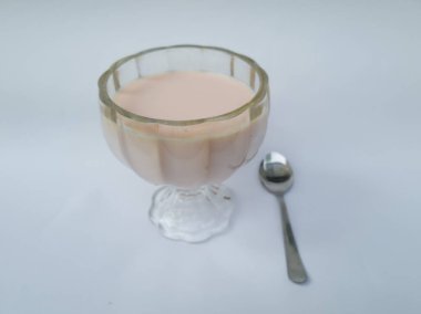 Beyaz arka planda cam bardakta çilek aromalı süt içilir.