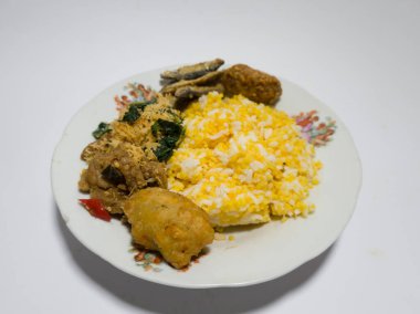 Mısır pilavı, kızarmış balık, yeşil sebzeler rendelenmiş hindistan cevizi serpiştirilmiş, tuzlu bir tabakta servis edilmiş.
